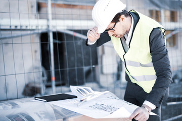 Mann im Anzug mit Helm und Weste auf einer Baustelle