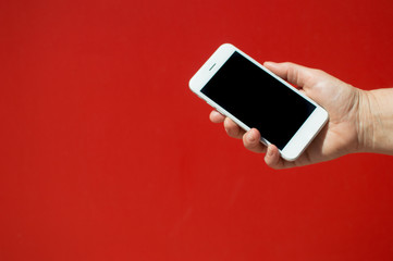 Close up on holding mobile smart phone over red background. Working remotely with information, modern communication lifestyle mock up display.