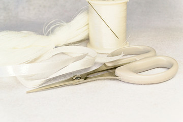 Fototapeta na wymiar items for creativity on a white background: scissors, threads, needle and ribbon