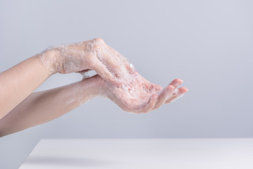 Washing hands. Asian young woman using liquid soap to wash hands, concept of hygiene to protective pandemic coronavirus isolated on gray white background, close up.