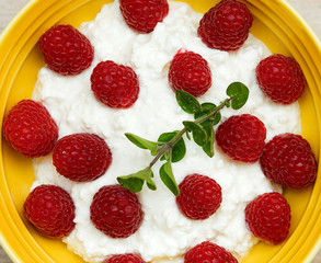 
Homemade cottage cheese with sour cream and raspberries, in a ceramic plate. Recipe for vegetarians.