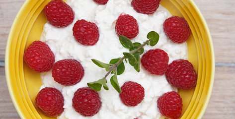 
Homemade cottage cheese with sour cream and raspberries, in a ceramic plate. Recipe for vegetarians.