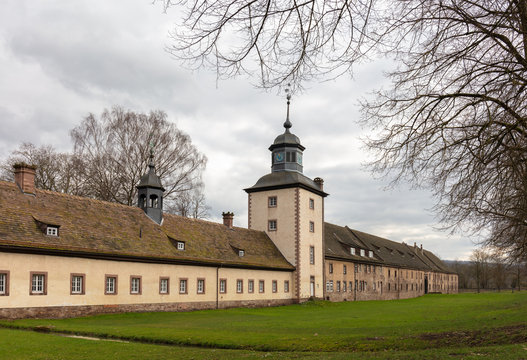 The Corvey Castle in eastern North Rhine-Westphalia near the town of H&ouml;xter. You can see the western outside with a tower. It is a cloudy winter day, the trees have no leaves.
