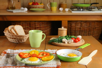 Fototapeta na wymiar Fried eggs and fresh vegetables on the wooden table in kitchen.