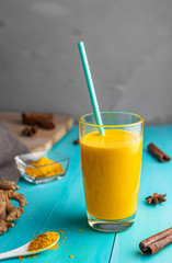 golden milk, milk with turmeric, spices. on a blue wooden background.