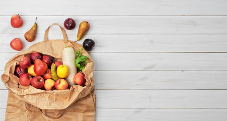 Different fruits , vegetables in paper bag on wooden background, copy space, flat lay. Grocery shopping concept, zero waste. Package-free food shopping, eco friendly natural bag with organic products.