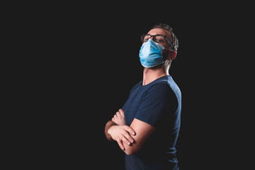 Adult person with protective face mask posing on a black background - social issues with virus and...