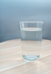 Glass cup with mineral water on a wooden tray. Close-up