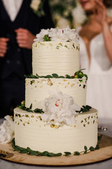 wedding cake stands on a served table and is decorated with flowers