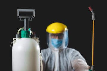 Naklejka premium Person with protective antiviral mask, suit, helmet and chemical decontamination sprayer bottle in home isolation.