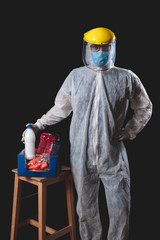 Food and groceries home delivery, pandemic outbreak hysteria, person in a full protective suit uniform holding a box with supplies.