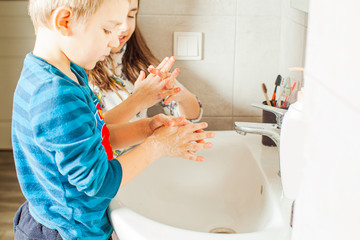 Brother and sister learning to wash hands at home