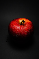 Fototapeta na wymiar red apple with drops of water on a black background