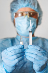 Close up of doctor hand holding vaccine. Medical equipment. A doctor wearing personal protective equipment including mask, goggle, and suit to protect COVID coronavirus infection.