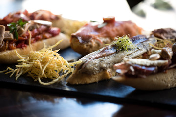 Tapas (varias)  con pescado rojo y blanco, pimienta roja, salmón y perejil. Deliciosas tapas españolas servidas en un plato de pizarra. Restaurante, bar.