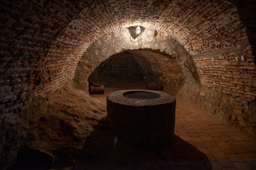 Dark corridors of old time castle dungeon light with few lamps and well