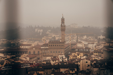 Palazzo Vecchio and the centre of Florence seen through the metal fence from the dome of Florence Cathedral on a foggy day