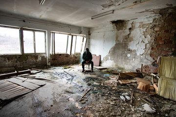 Dramatic portrait of a man wearing a gas mask in a ruined building.