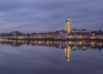 A nightly view on the Dutch hanseatic city of Deventer, in the central-east part of the Netherlands. Blue based evening skyline photo with Deventer cathedral tower and original old properties.