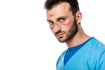 bearded doctor with marks on face looking at camera isolated on white