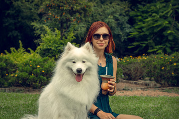 Redhead model posing with gorgeous Samoyed dog in the park.