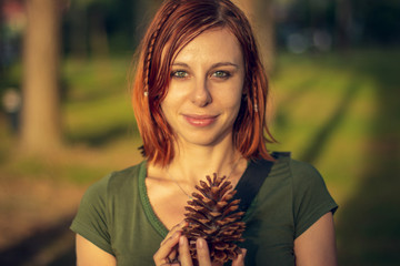 Redhead model posing and holding a pine cone