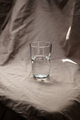 Composition glass cup half filled with water on a cloth background. Soft light.