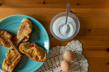 Photography from above of a typical Spanish dessert eaten during easter. Morning shot.Cinnamon,eggs,bread, sugar. Wood background.