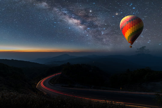 Hot air balloon flying over Chiang Mai Viewpoint Thailand under the sky with milky way and shininng star at night (with grain)