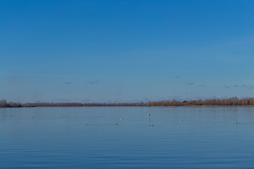 a large lake with blue water and blue sky in early spring