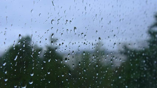 Raindrops hitting glass window during thunderstorm. Water drop texture