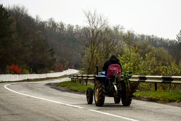 Obraz premium Man on tractor climbs mountain asphalt road.