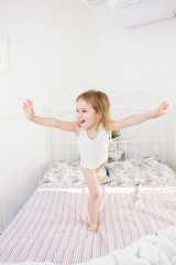 little girl jumping on the bed in parents bedroom.