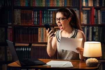 Stress. A young Caucasian woman holds documents in her hands and shouts into the phone. Home environment. The concept of self-isolation and remote work during quarantine