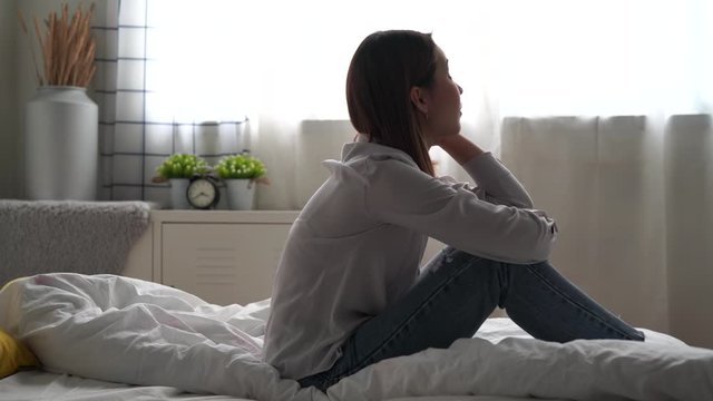 Depression and psychological problems, Young Asian woman is sitting in bed alone, She felt lonely and unhappy.