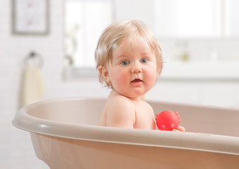 A Happy toddler bathing in bathtub.