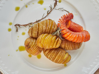 patatas asadas estilo hasselback sobre plato blanco vista desde arriba