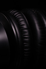 Macro details of black leather headphones on black background