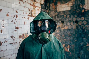 Dramatic portrait of a man wearing a gas mask in a ruined building. 