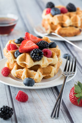 A close up view of a stack of Belgian waffles topped with berries ready for eating.