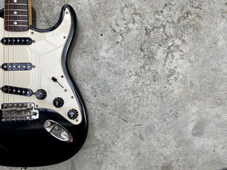 vintage black electric guitar on grey concrete with space. concept for wallpaper and writing text