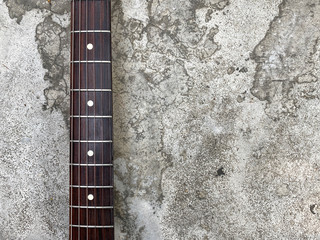 Rosewood guitar neck on old grey concrete with space. concept for wallpaper and writing text