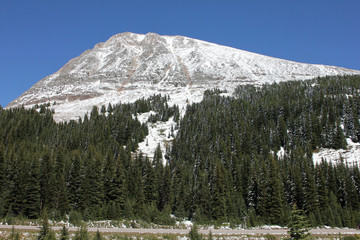Tree and snow covered mountian in Alberta, Canada with a road way at the base.