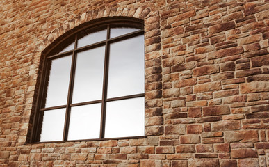 large arch-shaped window with reflective glass and a binding on a stone wall. Copy space for inscriptions. The concept of self-isolation and stay home during the coronavirus pandemic