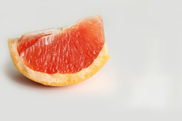 одна долька красного грейпфрута на белом фоне