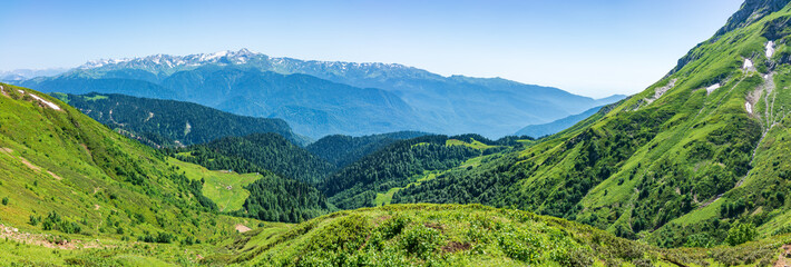 Plakat Panoramic view over the Green Valley, surrounded by high mountains with snow on a clear summer day.