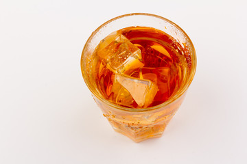 Glass of scotch whiskey and ice over white background.