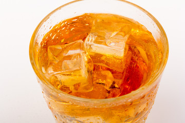 Glass of scotch whiskey and ice over white background.