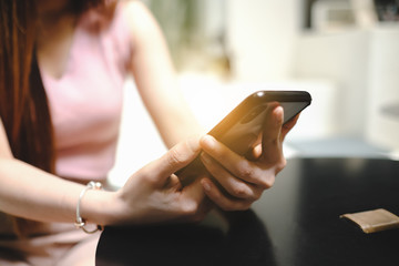 Blurred a woman holding a smart phone, side view at cafe.