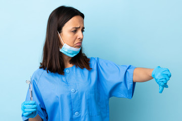 Young brunette mixed race dentist woman holding tools over isolated background showing thumb down with negative expression